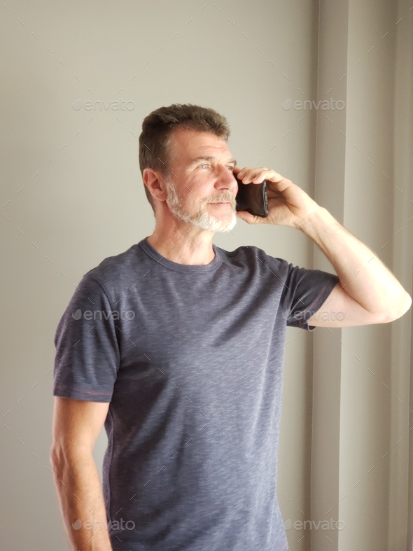 Grey haired bearded man is confidently talking on the smartphone, concept business solutions, senior