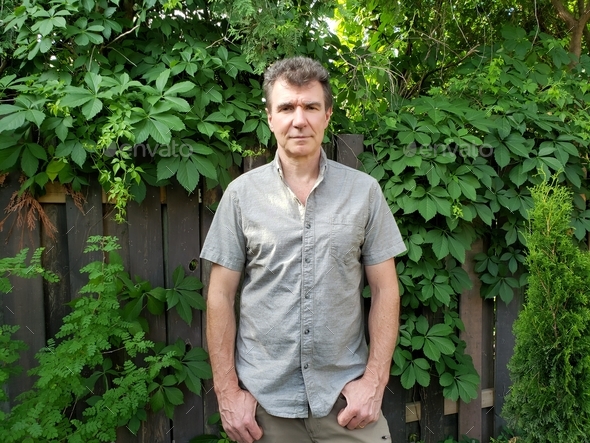 Man in plain shirt outdoor with greenery in background  - Stock Photo - Images