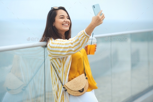 Cheerful and happy young overweight brunette woman 30-35 years old makes a selfie on a mobile phone