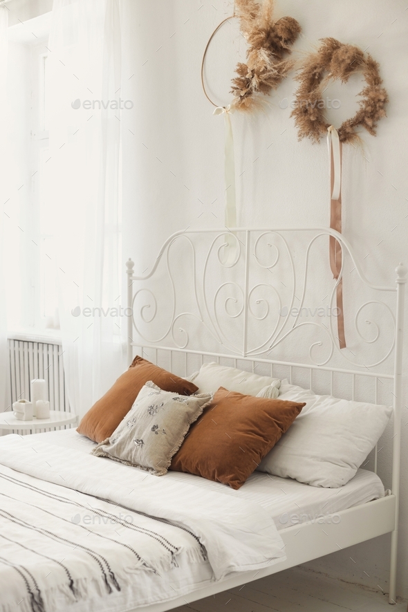 Wrought iron white bed in a cozy light bedroom with linens from