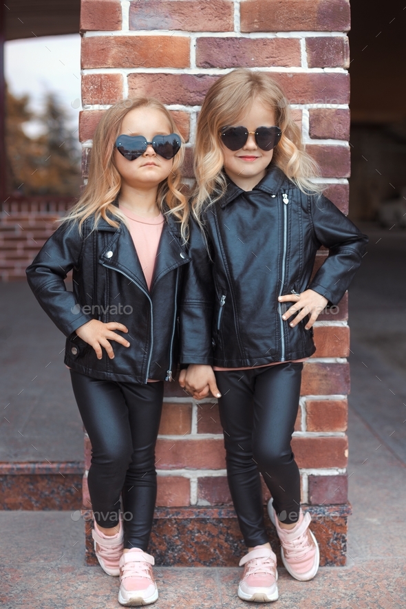 Urban family portrait of two cool stylish sisters in fashion