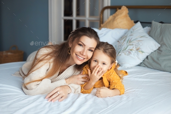 Beautiful Mom And Daughter Are Lying On The Bed And Smiling In A Cozy