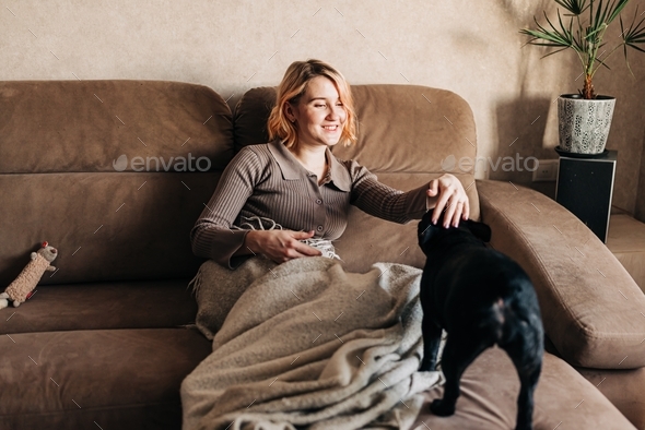 Young woman with her pet French bulldog on the couch lifestyle authentic people with pets