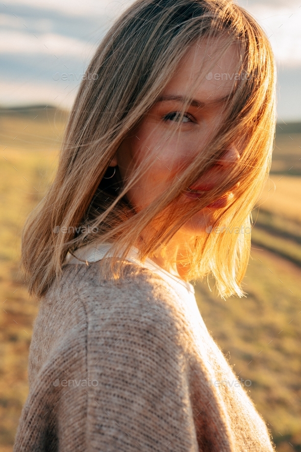 portrait of beautiful woman walking on field at sunset  - Stock Photo - Images