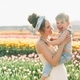 A mother holding a laughing little boy in a field of tulips in the spring. 