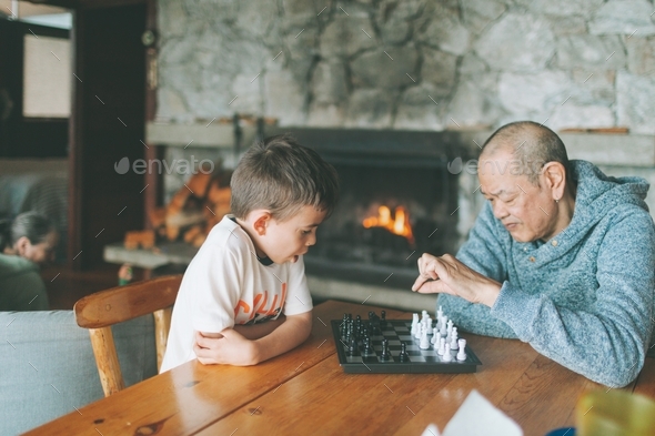 A grandfather and grand son playing chess together. - Stock Photo - Images