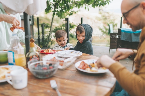 Two boys laughing while eating breakfast outside. - Stock Photo - Images