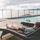 A little boy lounging and relaxing on a deck chair by a swimming pool by the ocean.  - PhotoDune Item for Sale