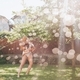 A woman holding a little boy while running through the sprinkler on a sunny summer day.  - PhotoDune Item for Sale