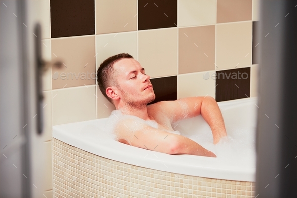 Contemplation in the bathroom. Young man relaxing in the bathtub full ...