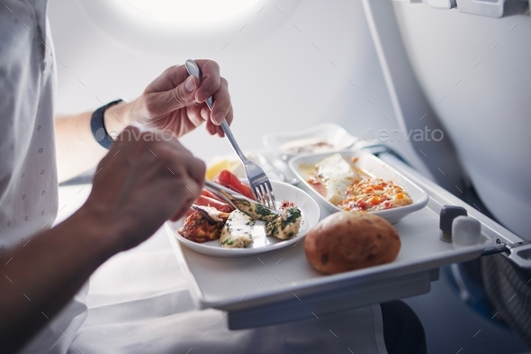 Passenger eating airline meal in airplane. Menu in business class on medium haul flight.