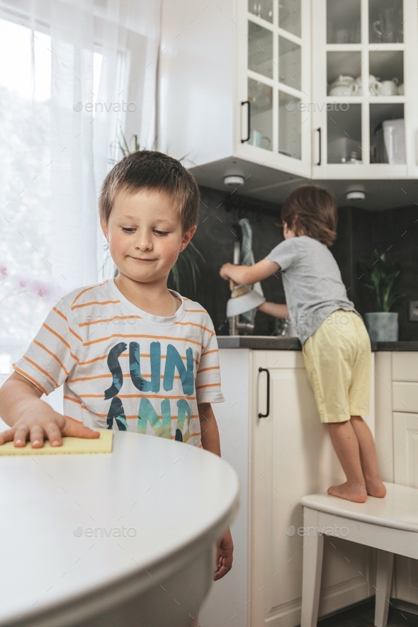 Children clean the kitchen, wash the dishes and wipe the table