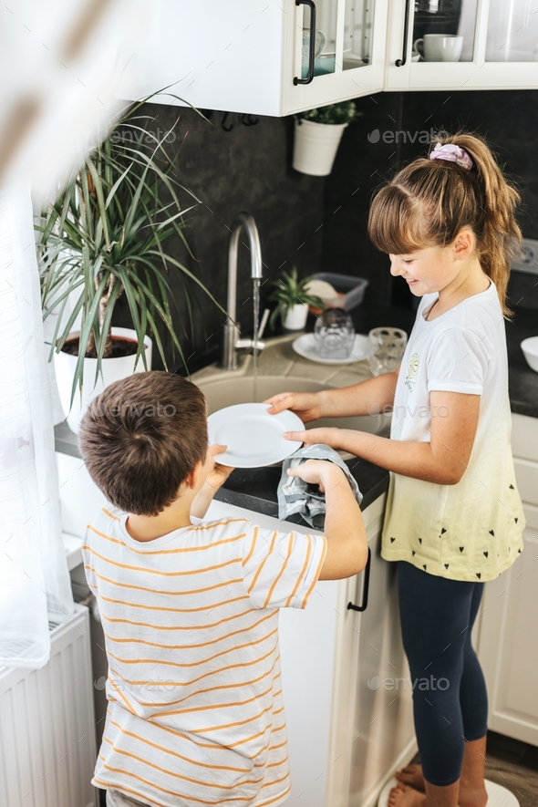 Children help to clean the apartment, wash the dishes in the kitchen