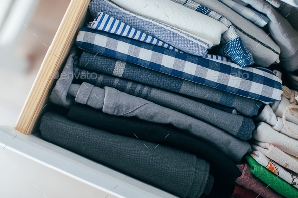 In a drawer a stack of neatly folded kitchen towels. Marie kondo method. Space organization concept