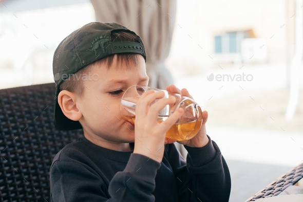 Boy drinking apple juice in cafe outdoor