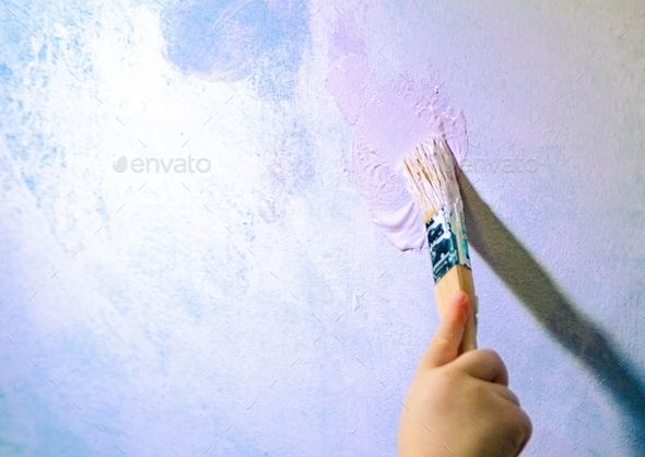 child draws on the wall with white paint, tool,