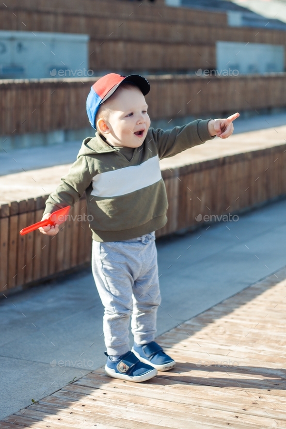 a little boy plays on the street, points to something with his finger