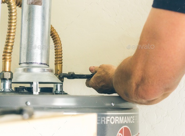 Adult male arm with wrench in hand making adjustments on hot water heater