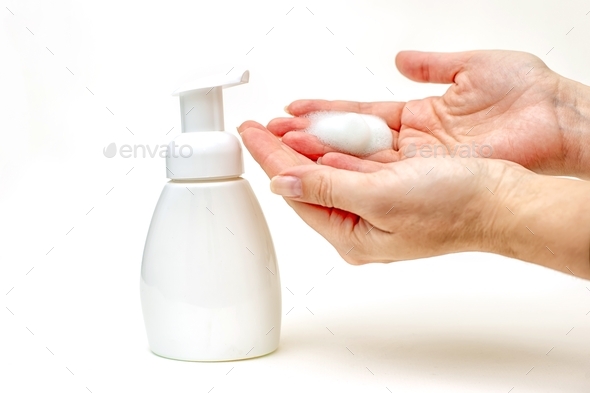 Hands of mature woman with foam of antibacterial soap on white b