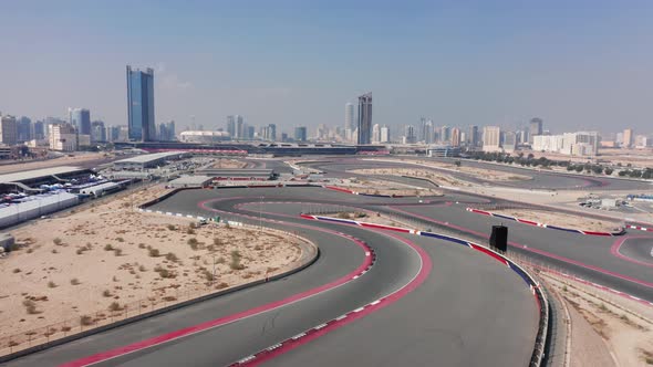 Aerial view of empty Dubai Autodrome race track, wavy corners, Dubai skyline