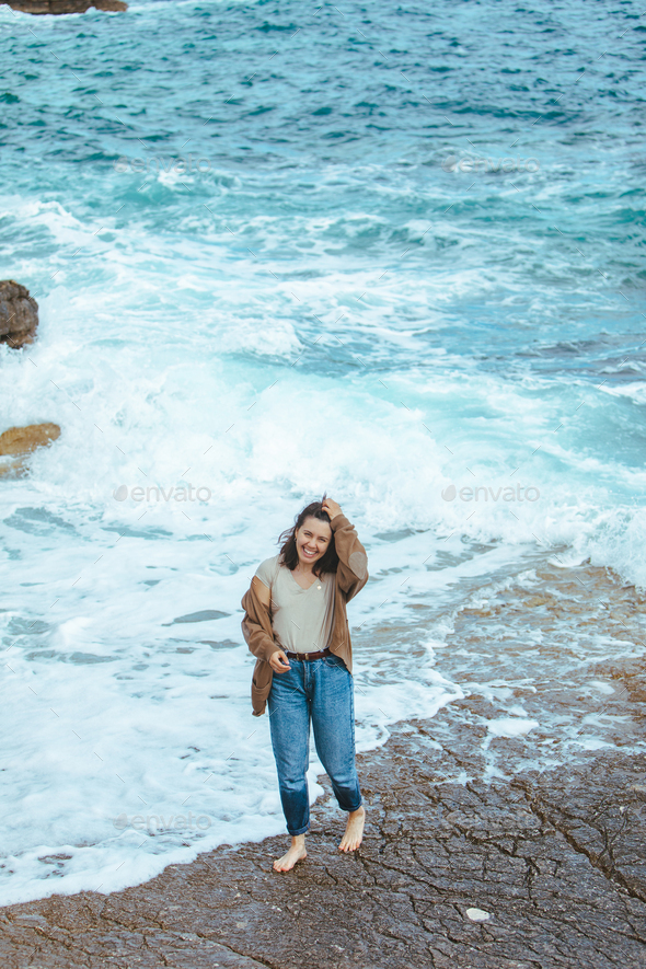 Land koppeling lade woman walking by rocky beach in wet jeans barefoot Stock Photo by  petruninsphotos