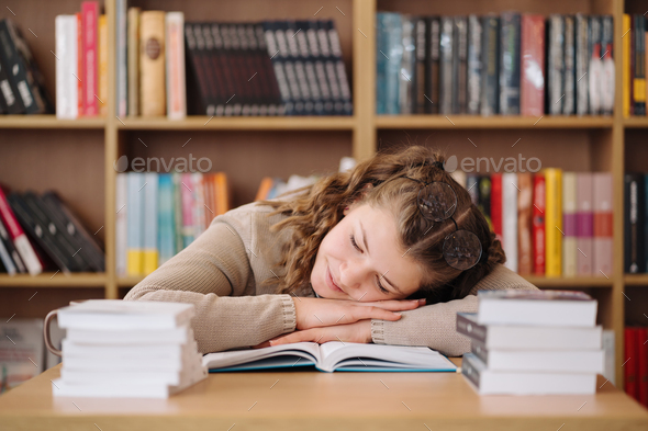 Tired student got asleep on the desk while studying among books - Stock Photo - Images