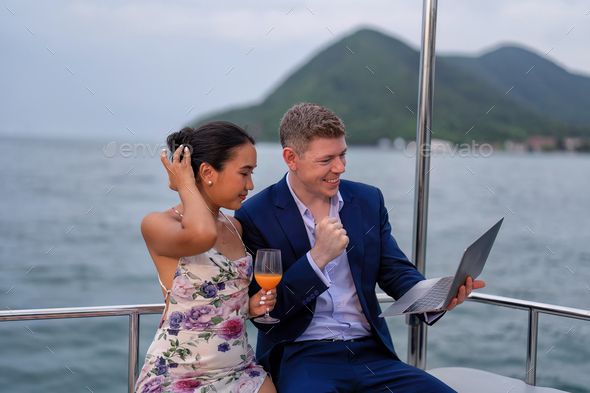 business man and wife on holiday in the yacht use laptop checking work happy congrats get good news