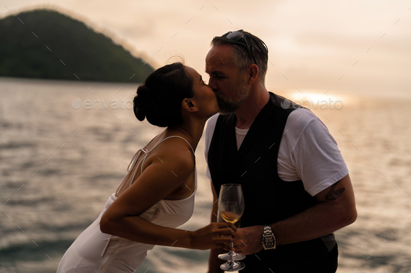 business man and wife on holiday in the yacht deck freedom celebration anniversary drink and kiss