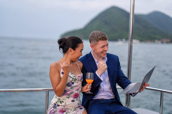 business man and wife on holiday in the yacht use laptop checking work happy congrats get good news