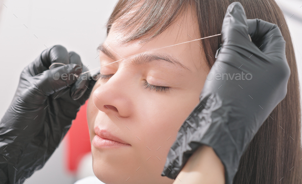 woman client in beauty salon during brow correction procedure.  marks on face of woman - Stock Photo - Images