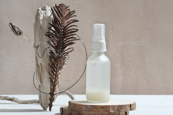 face care serum in white bottle on natural wooden podium next to modern still life set.  - Stock Photo - Images
