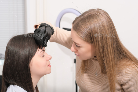 woman beautician making marks on client's face for brow mapping in salon. brow correction - Stock Photo - Images