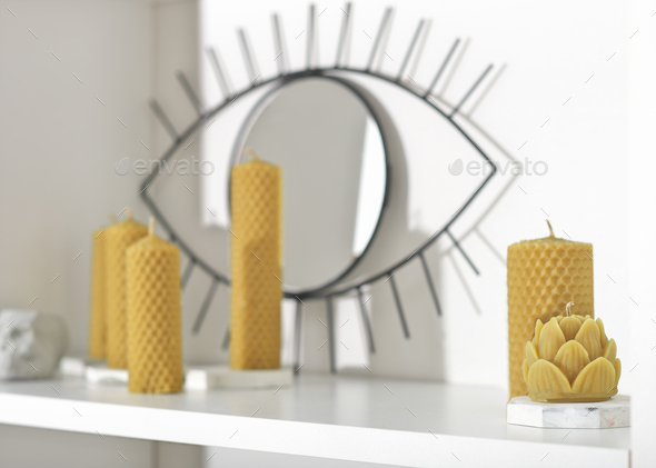 various beeswax candles on white shelf. handmade candles on concrete candlesticks - Stock Photo - Images