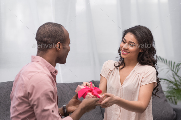 african american boyfriend presenting gift to girlfriend on international womens day