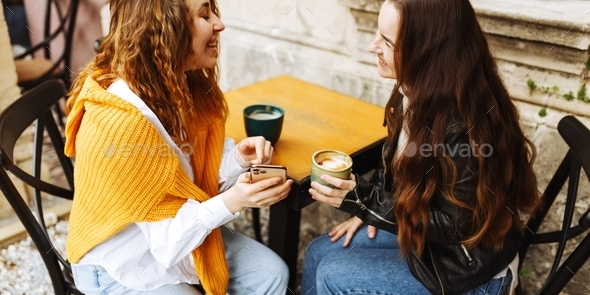 Cheerful female best friend share multimedia files on smartphones spending free time together