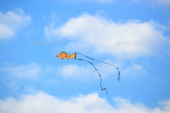 Colorful blue sky with white fluffy clouds and pops of color fish kite
