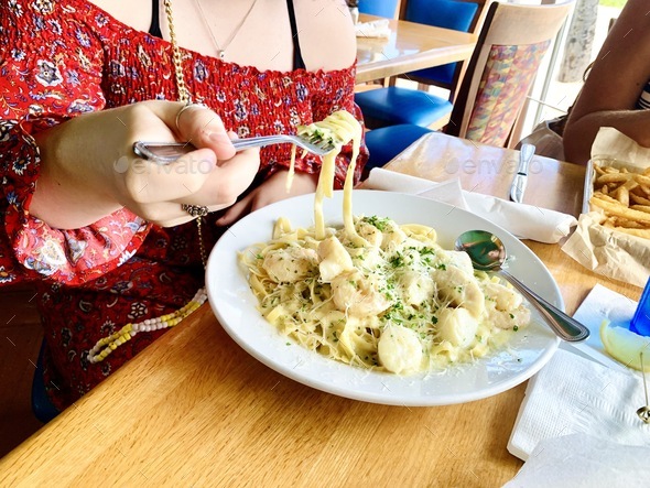 Taking a bite of chicken fettuccini Alfredo at restaurant dining out