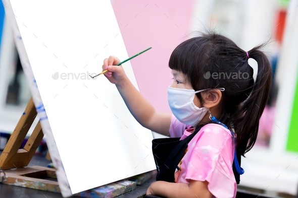 Schoolgirl are working on watercolor paintings on canvas. Student wearing white cloth mask.