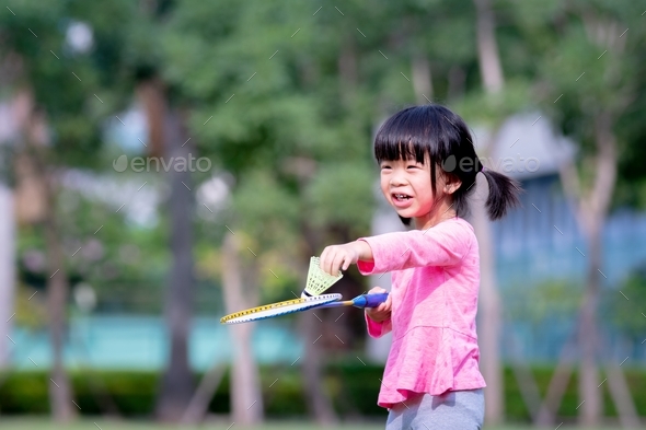 Sweet smile kindergarten girl preparing to serve badminton ball. Happy child play sport. Summer time