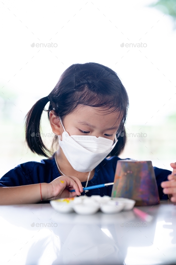 Portrait of cute girl wearing medical face mask. Kid learning art craft at outdoor.