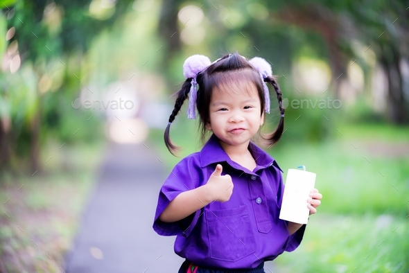 Student Asian girl holding a white milk carton box with blue tube straw.