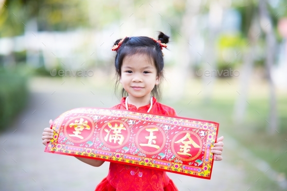 Portrait cute Asian girl holding Chinese New Year greeting card that means Wealthy and happy. - Stock Photo - Images