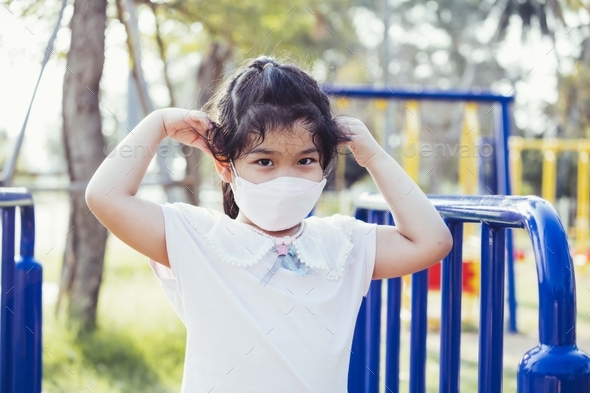Portrait child wear face mask while at playground. Prevent spread of respiratory virus.