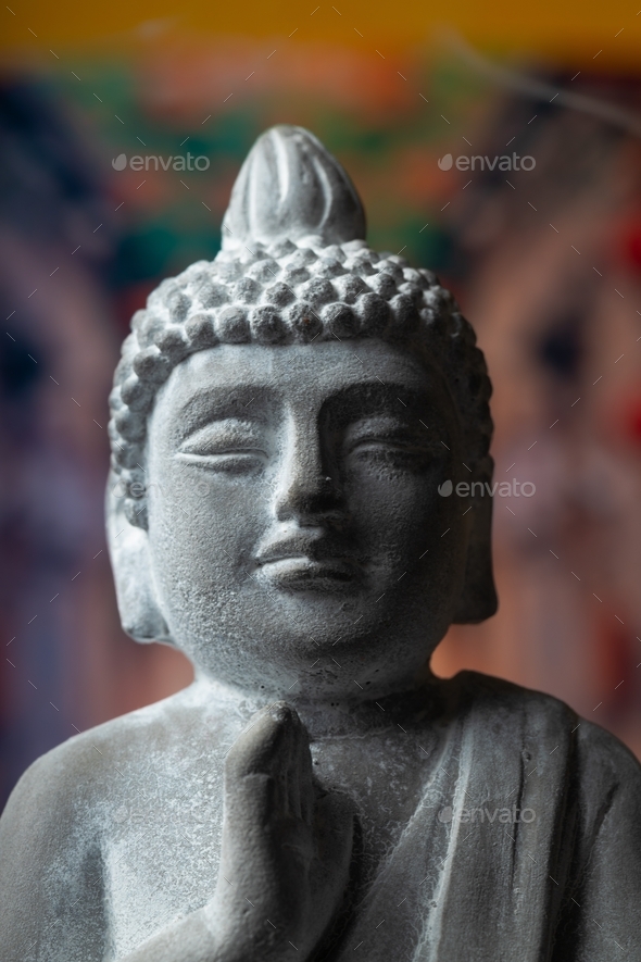 stone statue of buddha on a stone window sill surrounded by flowers and