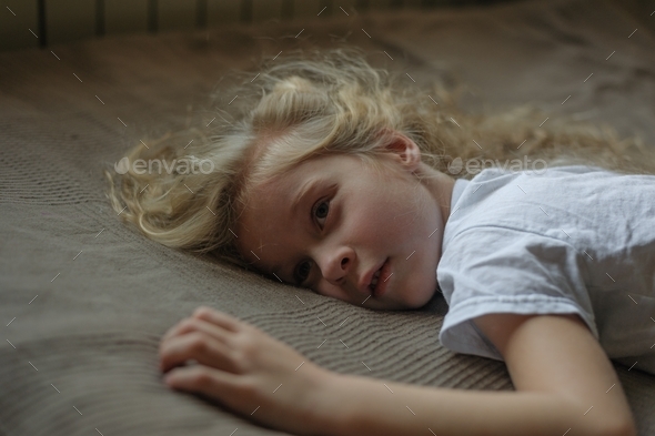 the child lies on the bed with a blank look in prostration Stock Photo ...