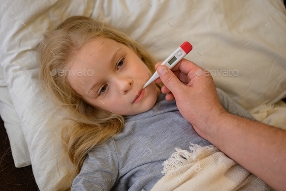 dad measures the temperature of his child, thinking that he is sick