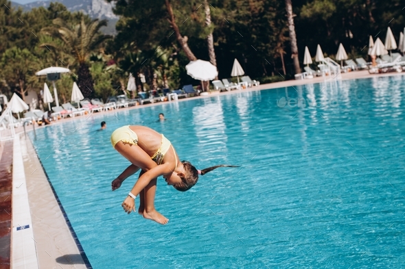 Little girl swim in the pool, jump into the water, somersault. concept of summer vacation