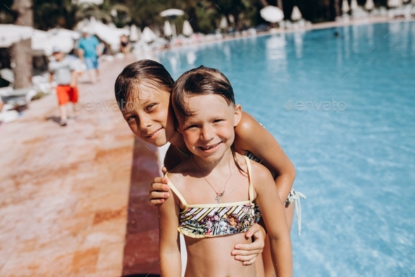 two sisters swim in the pool, jump into the water, somersault. concept of summer vacation