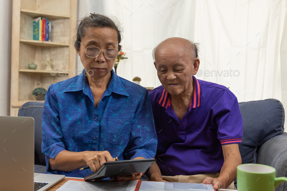Asian elderly sit and holding calculator for insurance or medical expenses and a computer