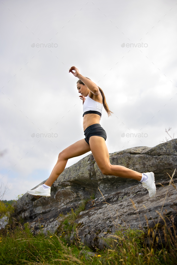 Side view of fitness woman doing high-intensity running on mountainside - Stock Photo - Images